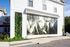Charming white building with elegant black-and-white mural and vibrant vertical garden, offering a stylish and inviting exterior.