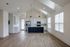 Modern kitchen with high vaulted ceilings, elegant white cabinetry, and a central island featuring pendant lighting. Bright and spacious layout with natural wood flooring and ample windows.