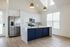 Bright modern kitchen featuring elegant white cabinetry, a navy island with gold fixtures, stainless steel appliances, and pendant lighting.
