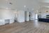Modern open-concept kitchen and living area with elegant white cabinetry, stylish hardwood floors, and chic pendant lighting.