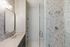 Elegant bathroom with modern fixtures, featuring a marble countertop, stylish hexagonal tile shower, and chic lighting.