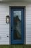 Sleek modern entrance with elegant blue door and stylish wall light on a pristine white facade.