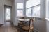Bright dining nook with modern wicker chairs, round table, and large windows showcasing a lovely neighborhood view.