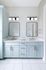 Elegant bathroom design with double vanity and modern light fixtures, featuring stylish blue cabinetry and gold accents.