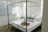 Bright and inviting bedroom with a modern four-poster bed, cozy cushions, and elegant decor, perfect for relaxation.