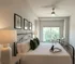 Inviting bedroom with elegant decor, featuring large windows, a comfortable bed, and chic artwork. Ideal for relaxation and natural light enthusiasts.