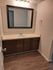 Contemporary bathroom with elegant wood cabinetry, a sizable mirror, and warm lighting, perfect for a chic living space.
