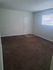 Inviting room with soft carpet flooring, sunlight streaming through a window, and a private entrance, ideal for cozy living.