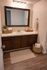 Elegant bathroom with a large mirror, sleek vanity, and warm lighting, showcasing modern fixtures and wooden flooring.
