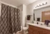 Bathroom with a vanity sink with extra counterop space, a toilet and then a tub with a shower curtain.