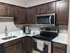 Sleek kitchen with dark wood cabinets, stainless steel appliances, and white countertops.