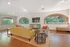 Bright and open clubhouse with large arched windows, comfortable seating, modern TV, and hardwood floors.