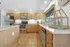 Spacious modern community kitchen with stainless steel appliances, wooden cabinets, and a large window view.