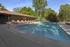 Picturesque outdoor pool surrounded by lush greenery and lounge chairs, offering a tranquil retreat.