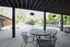 Charming outdoor seating area near a sunlit swimming pool with lush greenery.