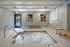 Indoor hot tub area with bubbling water, wooden benches, and a view of outside patio.
