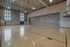 Spacious indoor basketball court with wooden floors and vintage brick walls.