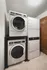 Stacked washer and dryer units in a modern laundry area with wooden cabinets.