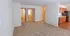 Bright living room with plush carpet and view into modern kitchen and hallway leading to bedrooms.
