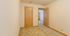 Spacious bedroom with plush carpet and natural light through open door.
