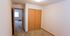 Bright and spacious empty bedroom with plush carpeting and wooden closet doors.