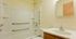 Contemporary bathroom with white bathtub, built-in shower, and elegant vanity.