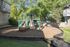 Inviting green and tan playground with climbing features and slide, surrounded by lush trees and residential buildings.