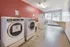 Bright and spacious laundry room with red accent wall, equipped with modern washing machines and natural light.