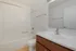 Bright modern bathroom featuring a sleek bathtub, elegant fixtures, and a spacious vanity.