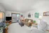 Inviting living room with a warm ambiance, featuring a plush sofa with red accent pillows, elegant decorative mirrors, and a modern glass coffee table.