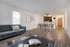 Inviting open-concept living and dining area with modern furnishings, cozy grey sofa, and elegant decor, leading to a stylish kitchen.