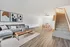 Modern living space with stylish grey sectional sofa, chic wooden coffee table, elegant dining area, and plush carpeted staircase.