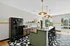 Chic modern kitchen with large windows, stylish pendant lighting, and a sleek black fridge complementing the elegant island seating.