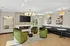 Sophisticated living room featuring elegant green chairs, a modern fireplace, and a stylish chandelier in a well-lit space with chic wall art.