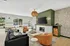 Elegant living room with large windows, featuring a stylish fireplace, chic green accent wall, and modern furniture, perfect for relaxation and entertaining.