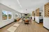 Bright and spacious modern interior with elegant wooden accents, featuring a large dining table, cozy seating area, and expansive windows with scenic views.