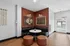Chic modern lounge corner with elegant decor, featuring a cozy black leather banquette, round white table, and stylish wall art, perfect for relaxation.