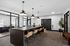 Leasing Office with sleek design, featuring a long table with padded stools, stylish pendant lights, and glass-walled offices.