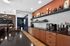 Modern kitchen area with sleek dark countertops, stylish wooden cabinets, and contemporary decor, featuring a cozy coffee station and elegant lighting.