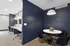 Modern interior space featuring a cozy round dining area with sleek black chairs and a stylish navy accent wall, accompanied by an inviting workspace with comfortable seating and contemporary light fixtures.