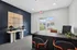Inviting office space with modern design, featuring a sleek desk, chic orange-accented chairs, and a stylish console table with decorative lamps against a deep blue accent wall, offering a view of a serene garden through glass doors.