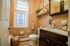 Charming bathroom with warm tile walls, elegant fixtures, and cozy accents. Bright natural light from the window enhances the serene ambiance.