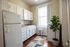 Charming kitchen with ample white cabinetry, modern appliances, and a sunlit window over a lush indoor plant.