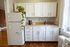 Charming kitchen with white cabinetry, a lush potted plant, and warm wooden floors, perfect for cozy culinary adventures.