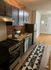 Charming kitchen with sleek dark cabinets, exposed brick wall, and modern stainless steel appliances.