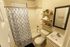 Contemporary bathroom featuring a sleek vanity, stylish shower curtain, and floating shelves with decorative accents.