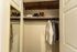 Spacious and organized closet featuring neatly hung shirts and a variety of shoes, complemented by a stylish mirrored door.