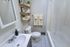 Elegant modern bathroom with sleek white fixtures, cozy towel racks, and stylish decorative shelving.
