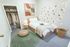 Cozy, well-lit bedroom with a modern single bed, decorative wall art, and elegant string lighting creating a tranquil vibe. Features a stylish open closet with organized hanging garments and a snug reading nook.