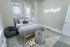 Charming bedroom with cozy bed, modern decor, and a glowing 'focus on the good' neon sign, creating a serene ambiance.
